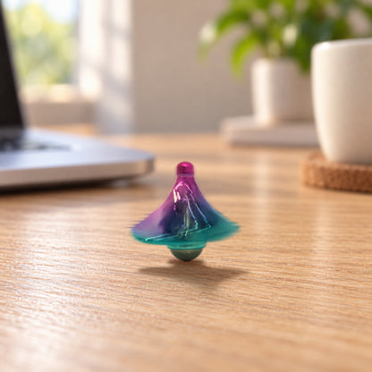 Purple-teal metal spinning top on a wood office desk